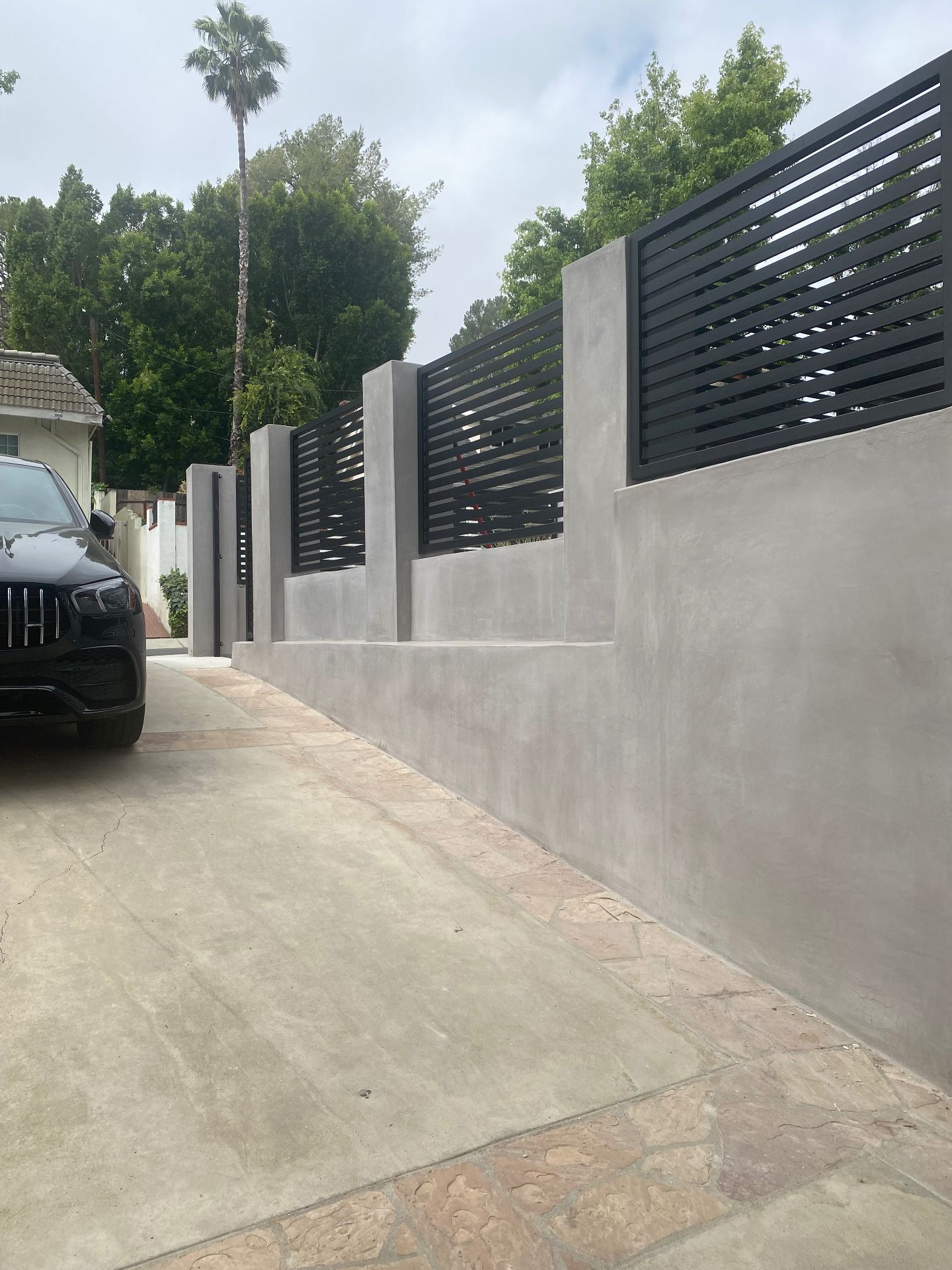 Smooth concrete perimeter wall with black slat privacy panels
