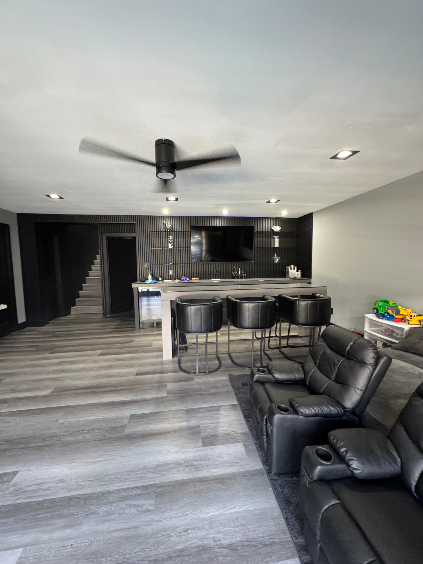 Remodeled pool and lounge room with black slat feature wall, wet bar, and theater seating