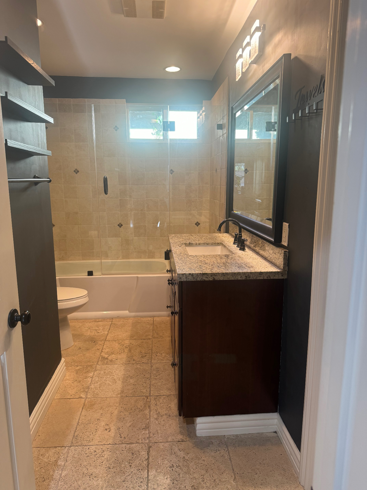 Dated bathroom with beige tile, tub, and dark vanity before Venegas Construction remodel