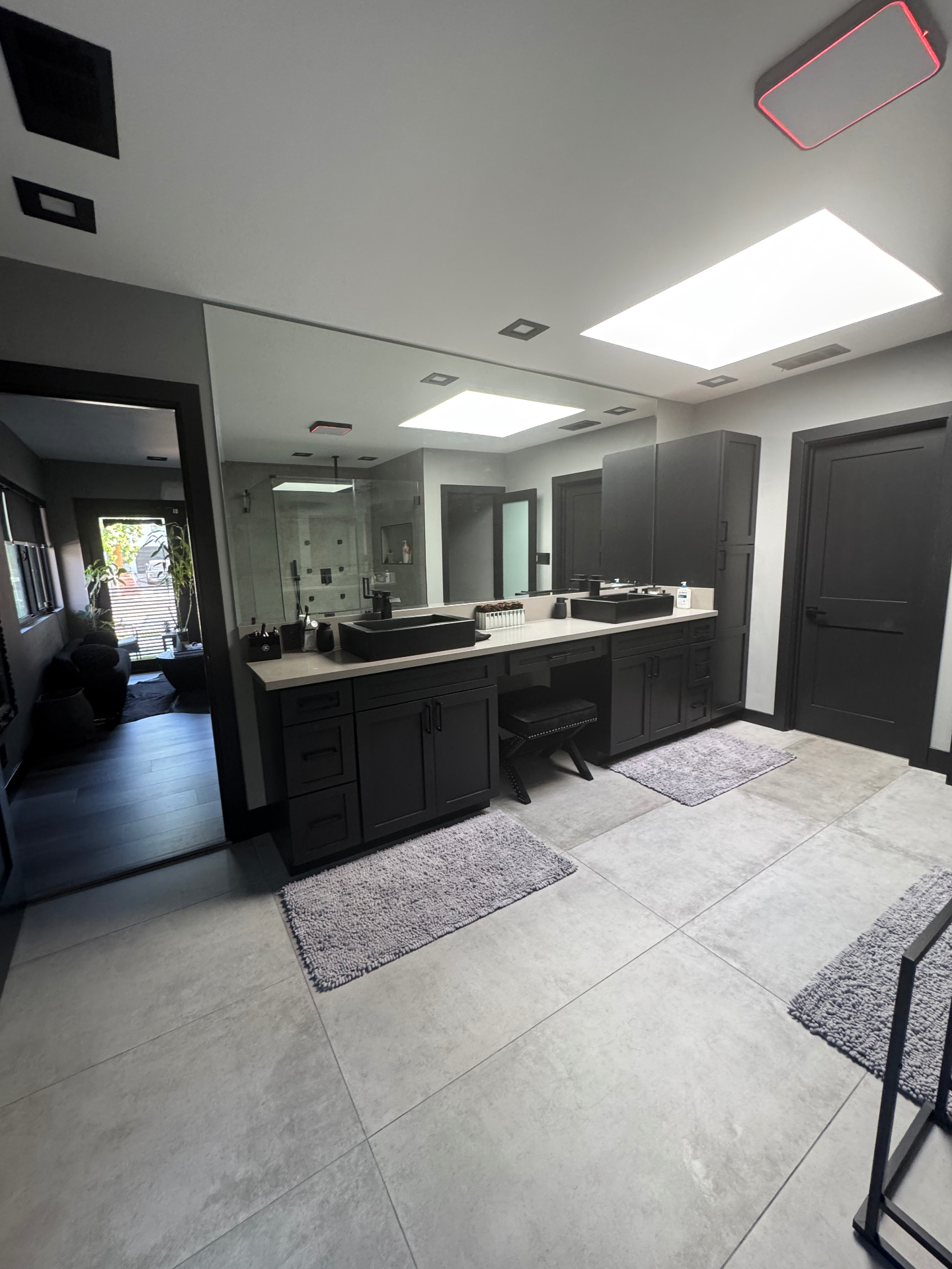 Master bathroom with dual black vessel sinks, floor-to-ceiling mirror, and dark cabinetry