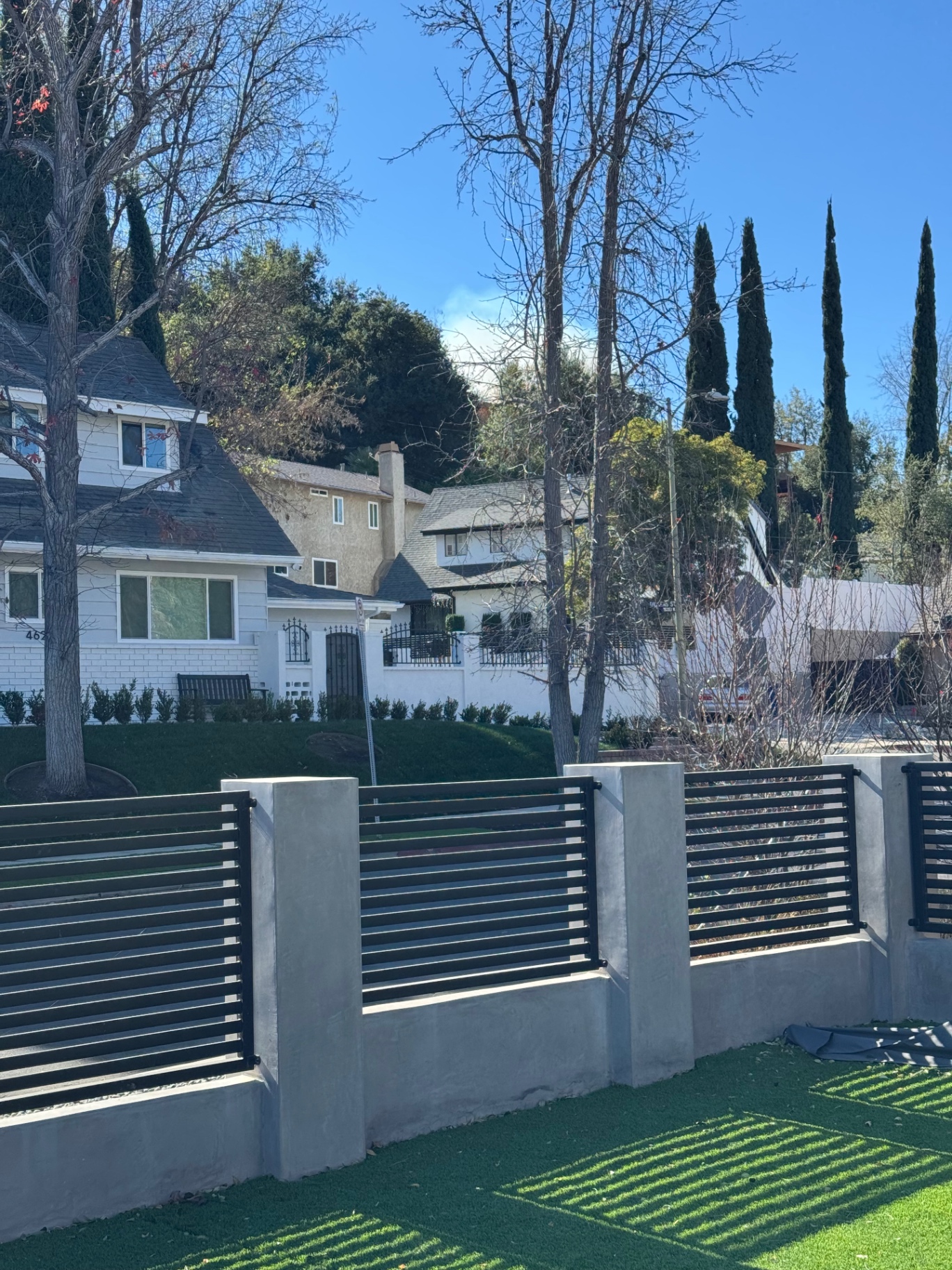 Home exterior showing roofline, siding, and windows behind a concrete privacy wall