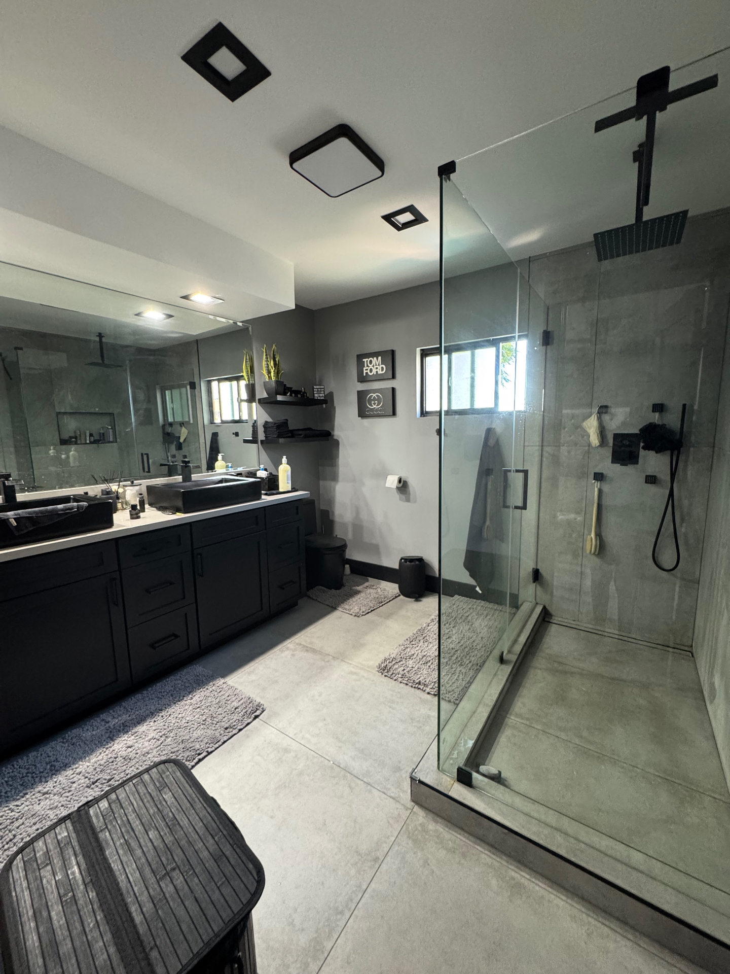 Modern bathroom with black vanity, walk-in glass shower, and concrete tile after Venegas Construction remodel