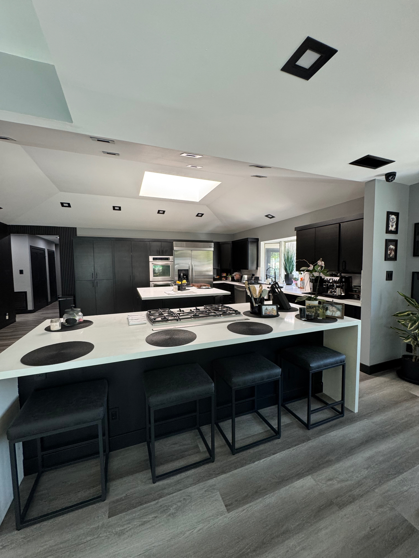 Encino kitchen after remodel with black cabinetry, white waterfall island, and vaulted ceiling
